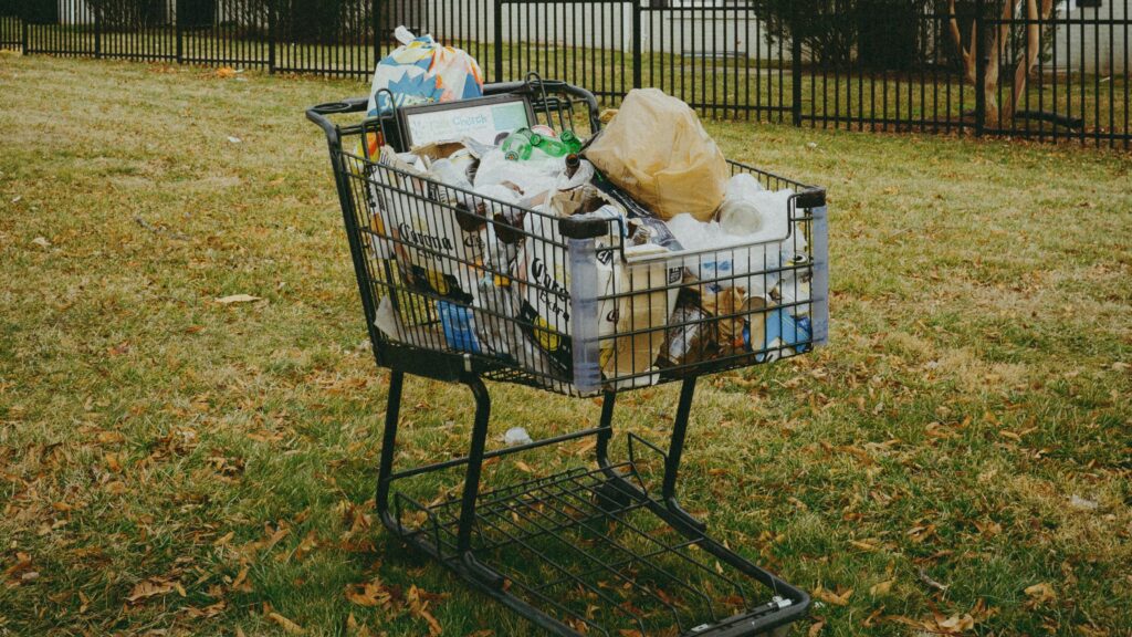 A shopping cart in a yard with a house in the background