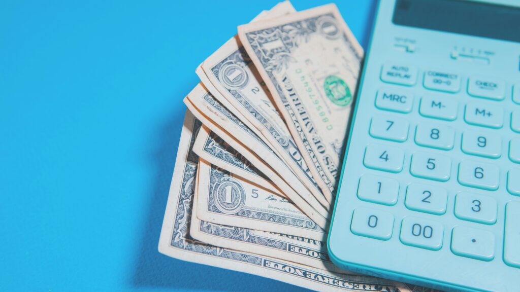 Us dollar bills and a calculator on blue background