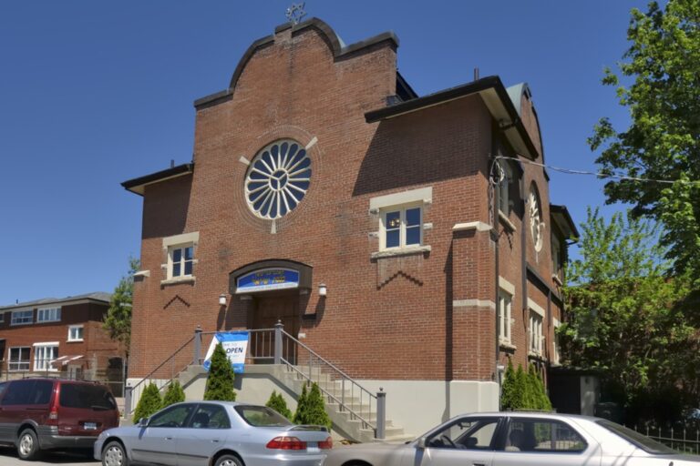 A red-brick synagogue building with a rosette window and gable facade