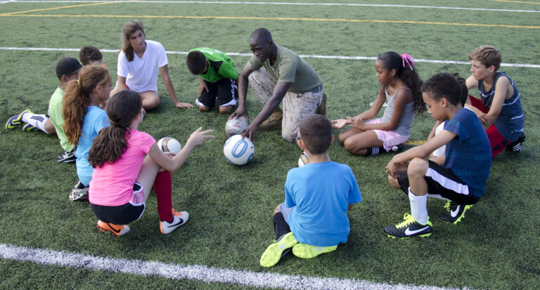 A coach talking with young children on a youth soccer field